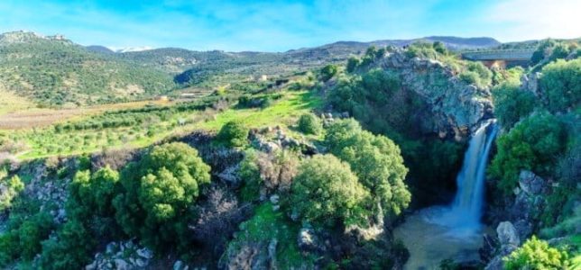 View of the Saar Waterfall, with Mount Hermon and Nimrod Fortress in the background, in the Golan Heights, Northern Israel